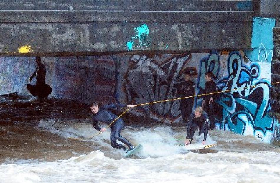 Surfers ride the current on the swollen Leith yesterday afternoon. Photo by Craig Baxter.