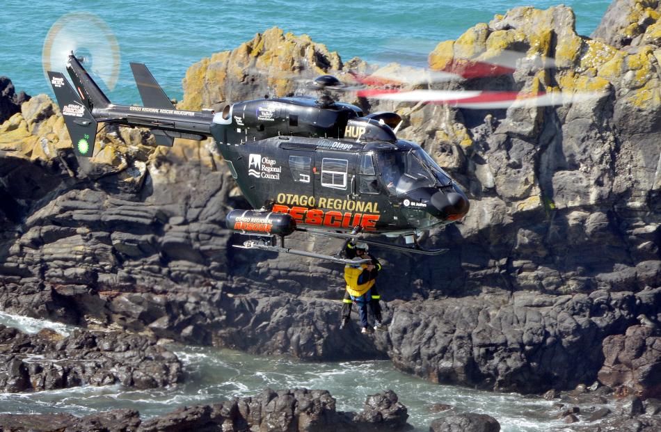 A rescue helicopter hovers above the rocks.