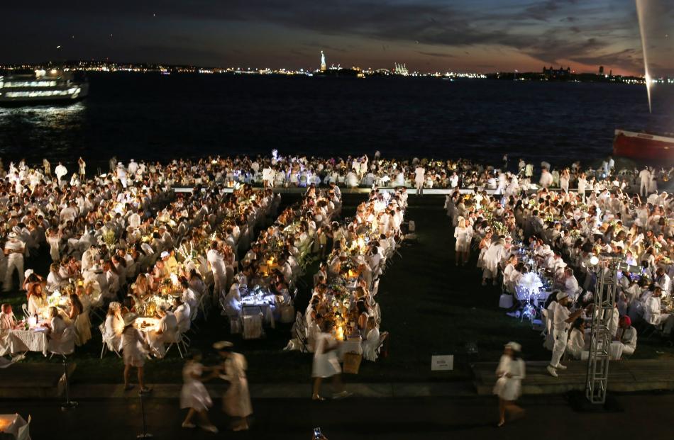 People attend Diner En Blanc, the French-inspired secret pop-up dinner, in Robert F. Wagner Jr....