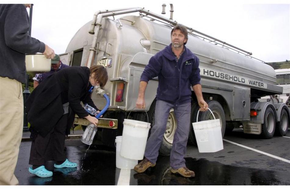 Macandrew Bay residents Ron Lee and Claire Gallop get their emergency water supply. Photo by Jane...