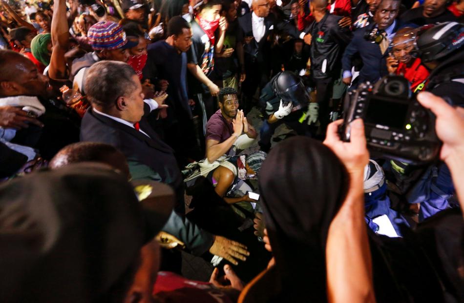 People surround a shooting victim in uptown Charlotte, North Carolina, during a protest of the...