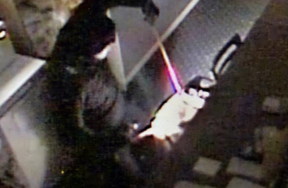 CCTV footage shows a burglar using a bar to jemmy open a safe at Grocery King.PHOTO: SUPPLIED
