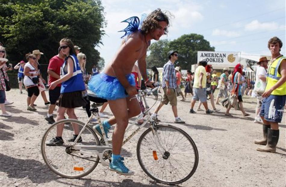 A man rides a bicycle in a tutu and fairy wings.