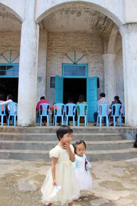 Two young girls play outside the Falam Baptist church, reputedly the largest church building in...