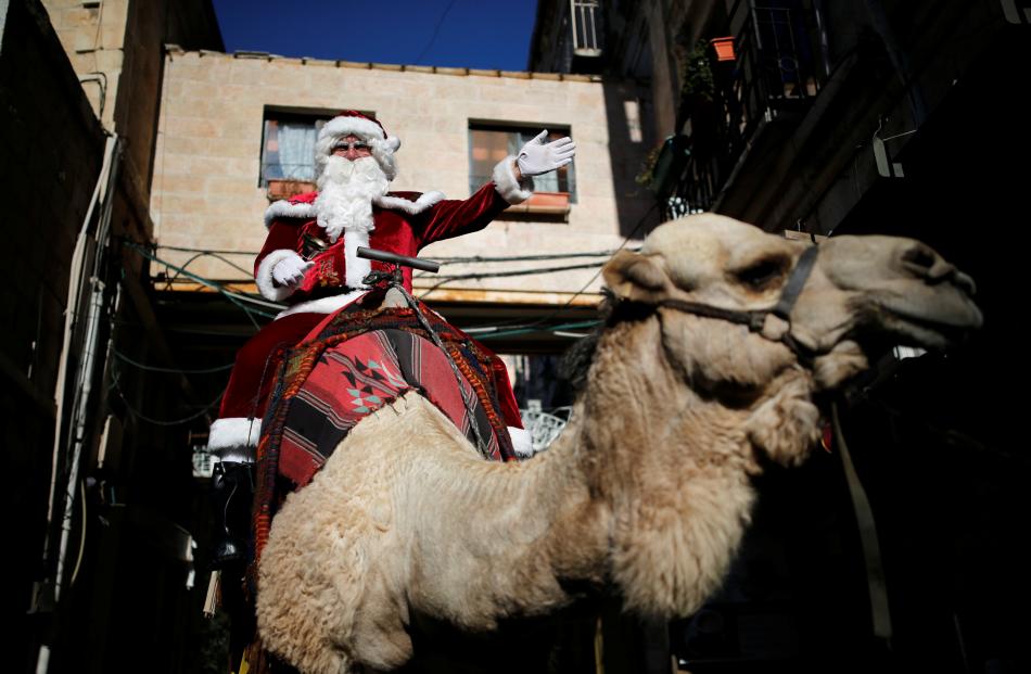 Israeli-Arab Issa Kassissieh dressed as Santa Claus as he rides a camel during the annual...