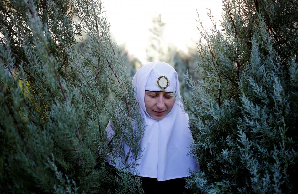 A nun with Christmas trees, handed out annually by the municipality, in Jerusalem's Old City....