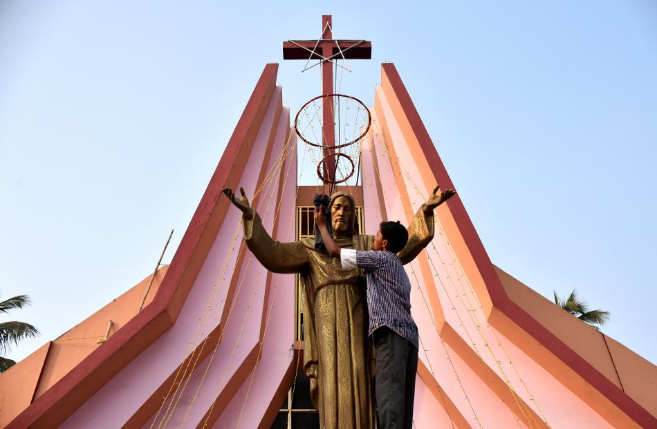 In India, a worker cleans a statue of Jesus Christ at a church in Guwahati. Photo: Reuters