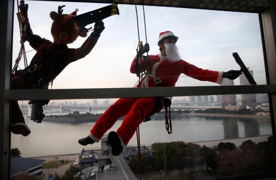 Window cleaners dressed as Santa Claus and a reindeer in Tokyo. Photo: Reuters