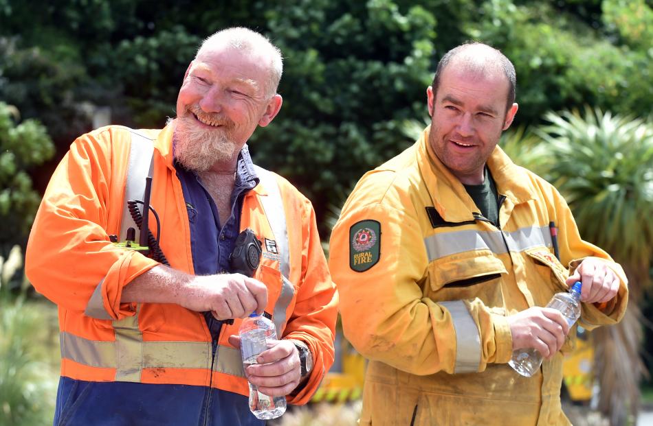 Pete Harrison (left), of Fulton Hogan, and Daniel Marsh, of the Otago Rural Fire Authority, share a joke with fellow volunteers during a break from ``mopping up'' the fire at Signal Hill yesterday. 