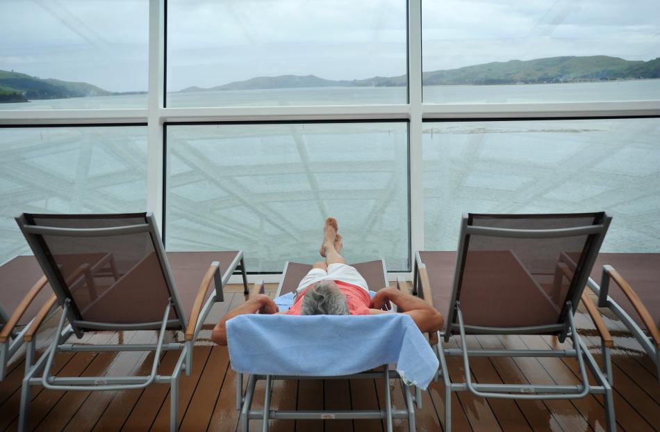 A passenger reclines on a deck chair in the solarium.