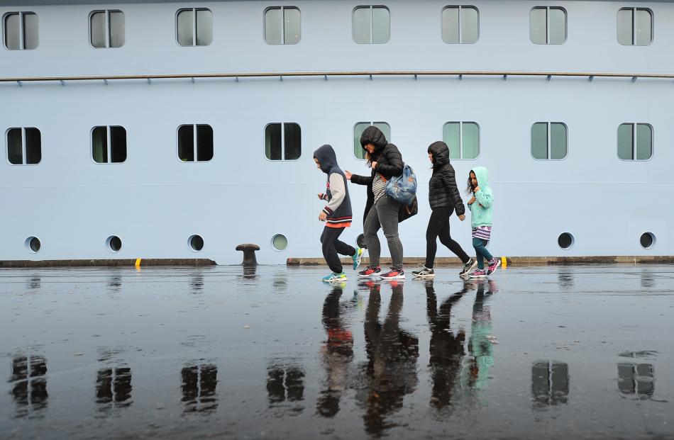 Passengers tread a soggy path past the ship.