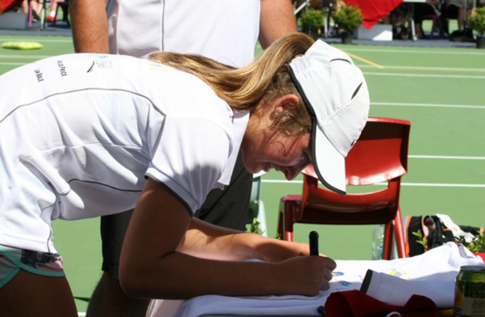 Emilia Price signing a t-shirt for auctioning to raise funds for the Te Anau Tennis junior players.