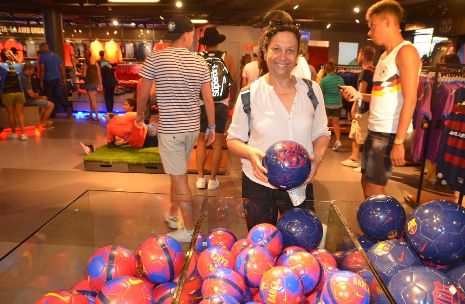 A tourist buys a football  from one of the many shops selling Barcelona FC souvenirs. PHOTOS:...