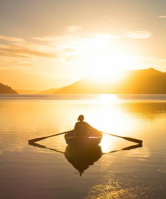 Tori Norman immerses herself in vitamin D while rowing under the setting sun in Otago Harbour. Photo by Samuel Bingham.