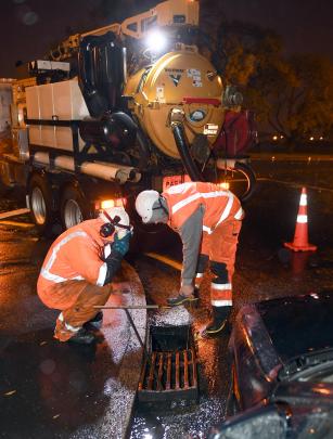 Downers workers clear a mud trap in Melville street in the early hours of this morning.  Photo:...
