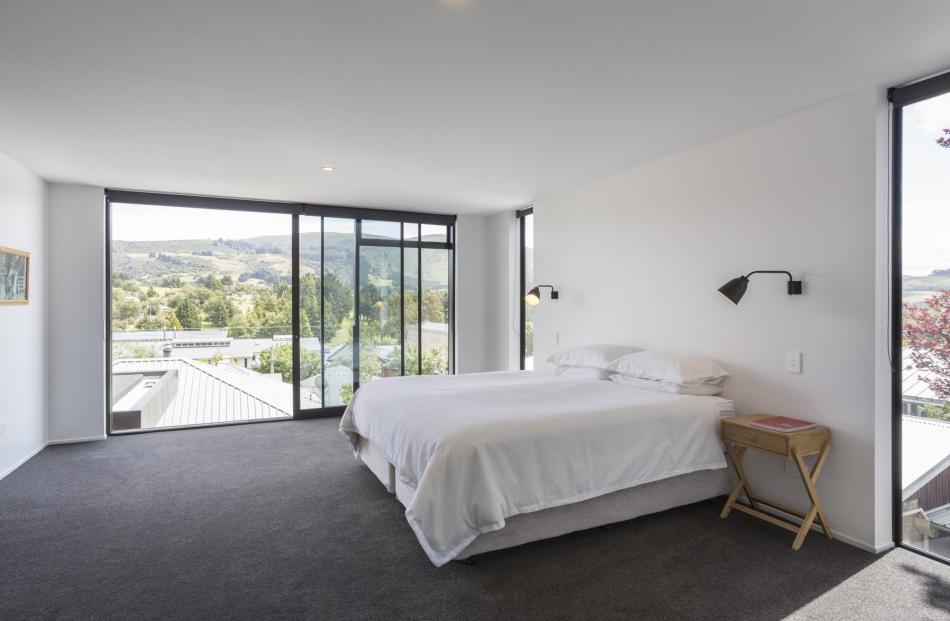 The master bedroom on the top floor has a glass stacking door with a half-height balustrade for safety. The owners never tire of the view out to Flagstaff. PHOTO: GRAHAM WARMAN