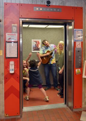 Tom Csima strums in a lift.