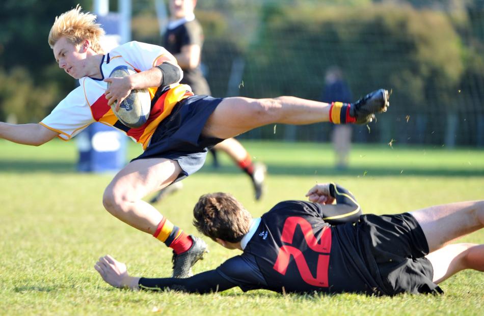Waitaki Boys' High School replacement Bayley Sullivan ankle-taps John McGlashan College back Andrew McKenzie during an Otago premier schools game at McGlashan on Saturday. Photo: Christine O'Connor.