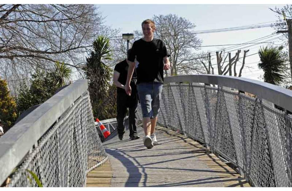 Ignoring warning tape closing a badly twisted footbridge over the Avon River, two boys cross to...