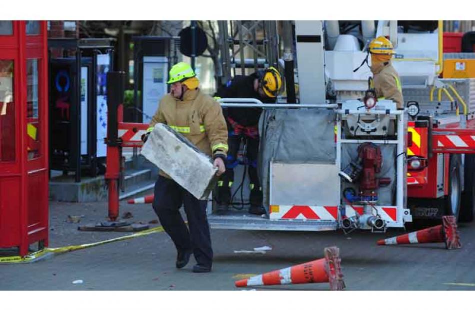 Firefighters removing loose bricks from the top of a heritage building inside the cordon...