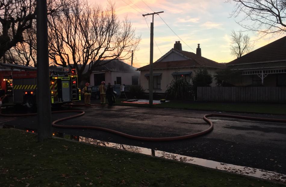 Emergency services attend a "well ablaze" house fire in South Dunedin. Photo: Peter McIntosh