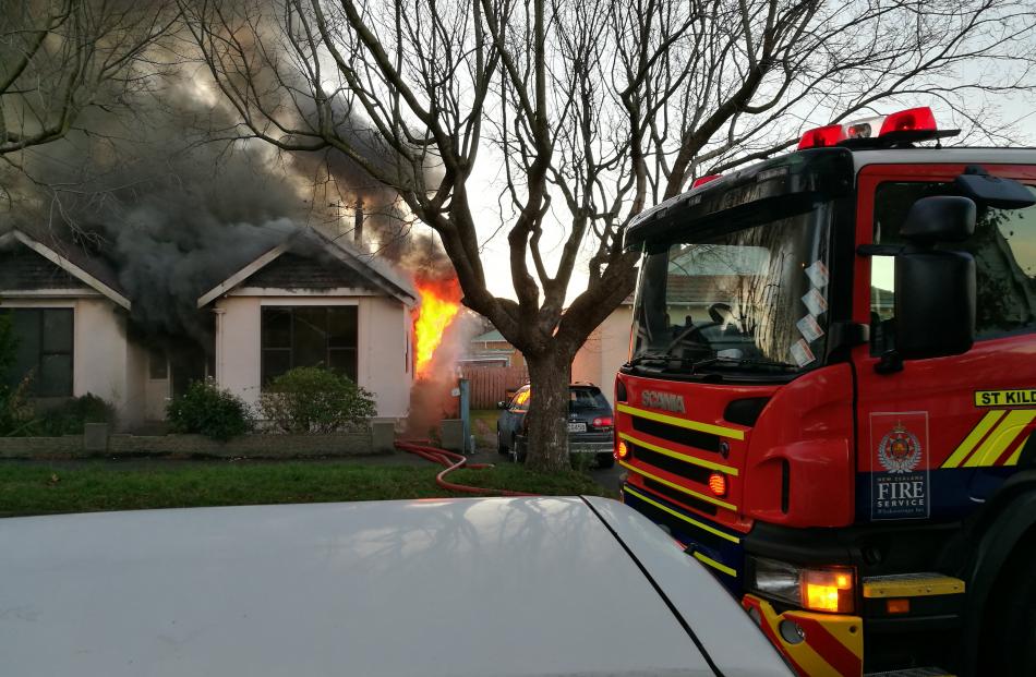 Flames can be seen climbing up the side of the house. Photo: Richard Lindsay