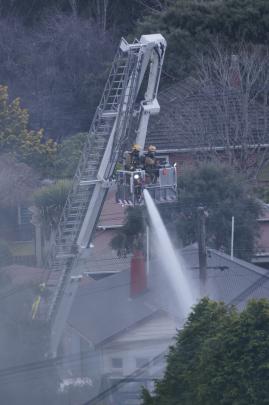 Firefighters dampen down the house on Sunday afternoon. Photo: Paul Smale 
