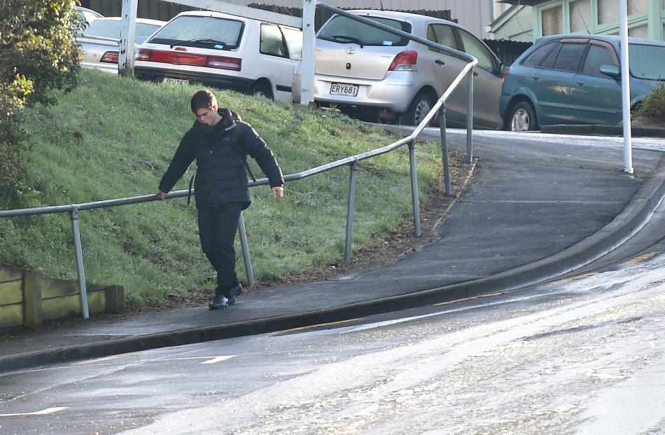 A pedestrian holds a handrail as he walks down the icy Filleul St footpath  in central Dunedin...