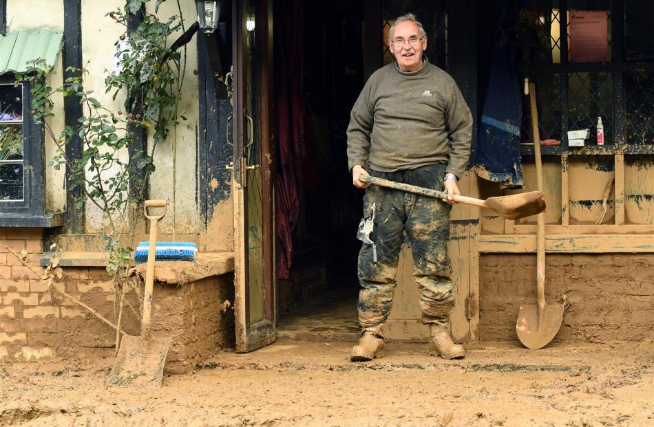 Mr Sasse is all smiles despite his home being surrounded by mud which was waist-deep. Photo: Stephen Jaquiery