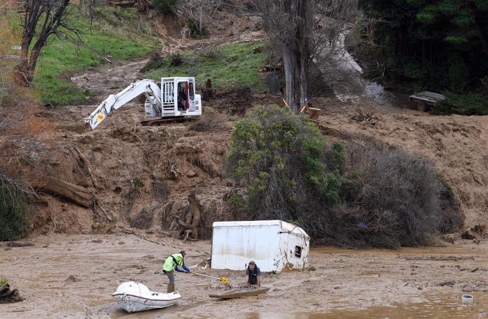 Daniel Prattley (left) and Peter Scott work to remove Mr Sasse's trailer from a lagoon at the foot of his property after the slip gouged the hillside, discarding plantings and possessions along a kilometre-long path of destruction.