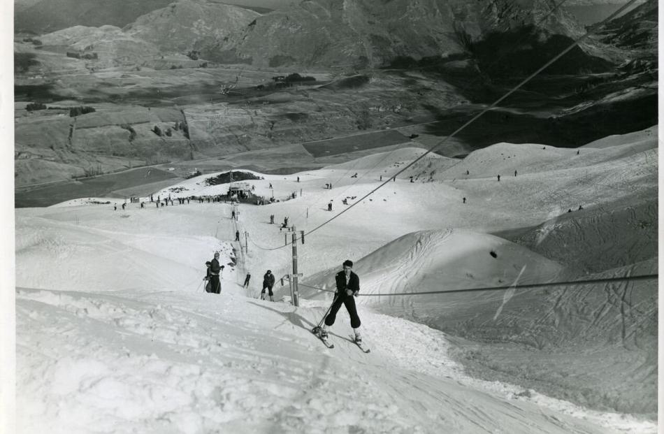 Skiers use the Hamilton rope tow at Coronet Peak during its first years as a commercial skifield.  