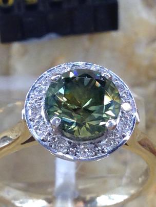 A 1.8 parti (mixed colour) sapphire mined and cut by Mr Litchfield is surrounded by diamonds in...