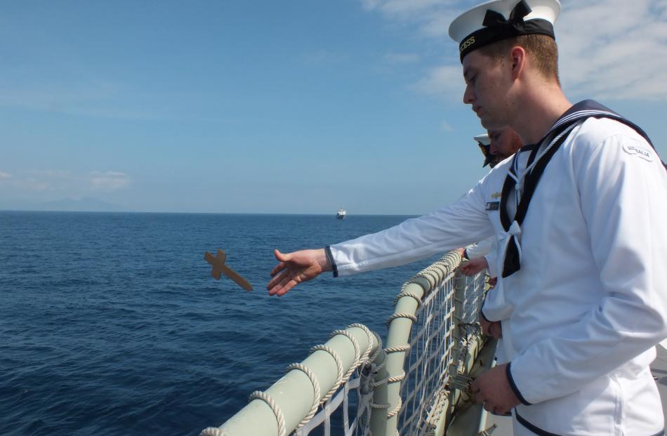A sailor on HMAS Success throws a cross representing one of the lives lost on HMAS Canberra.