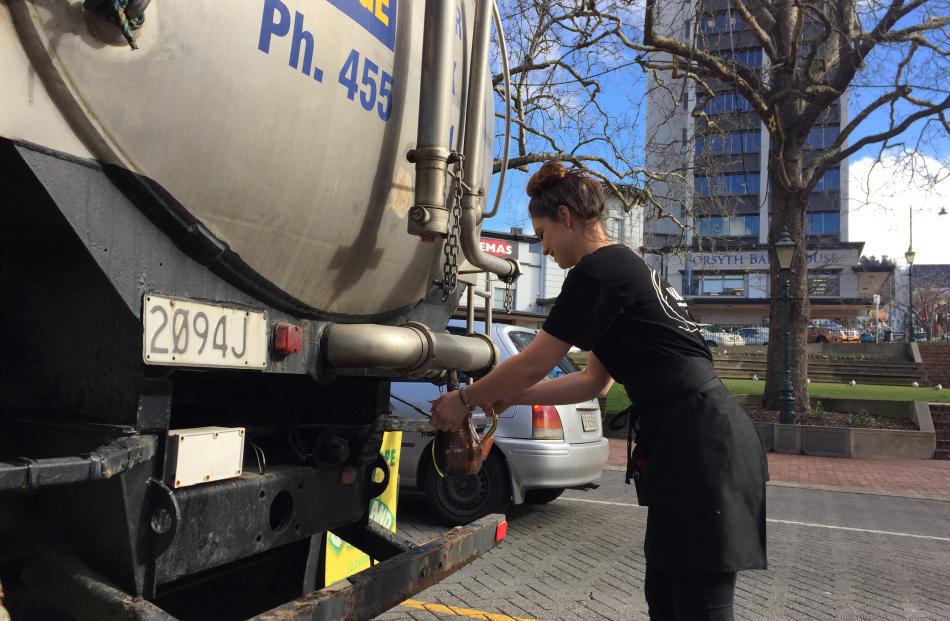 A hospitality worker gets water from a tanker in the Octagon. Photo: Chris Morris