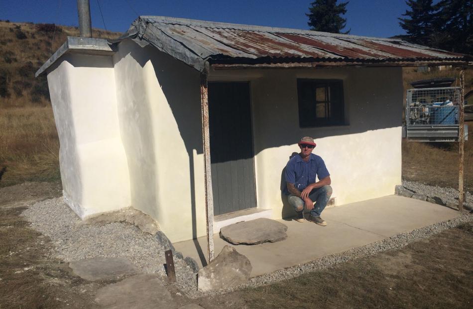 Earth plasterer Liam Flannery at the restored historic miner's hut in the Department of Conservation's Golden Point Reserve near Macraes. Photos: Supplied