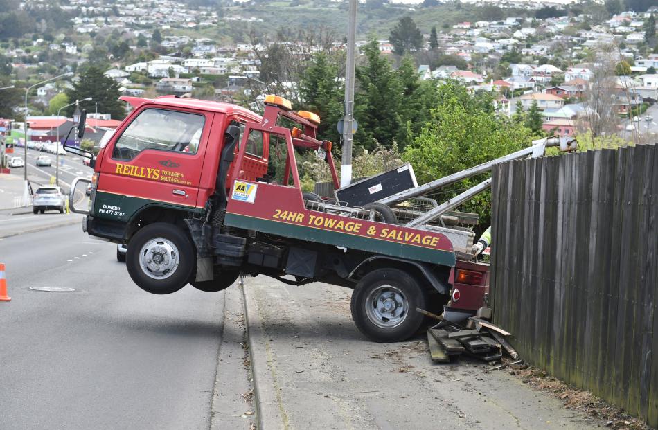 The front wheels of a tow truck lift during an unsuccessful attempt to extract an SUV from down a bank in Stuart St yesterday. Photos: Gregor Richardson