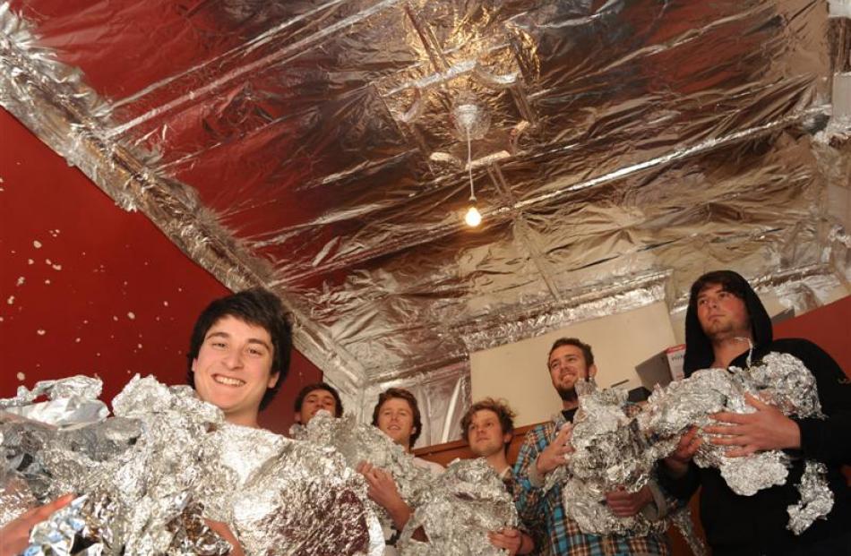 Hamish Chang (left) cleans tinfoil from his room last night, helped by flatmates (background,...