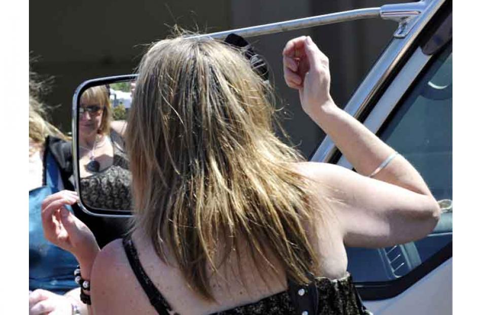Jill Kennedy makes use of a van mirror to adjust her hair.