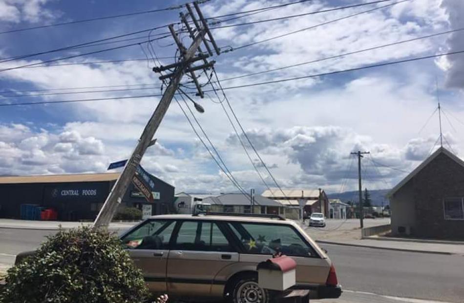 A fallen power pole on Chicago St, Alexandra, leans over a car on Saturday. The pole was replaced on Sunday. Photo: Supplied