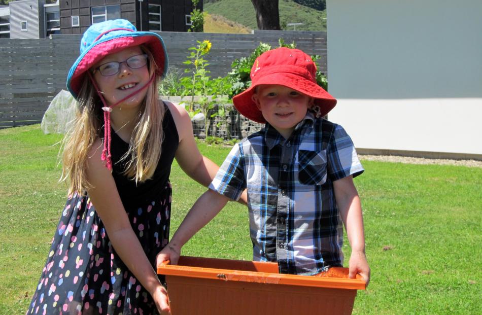 Brooke (6) has her finger in the drainage hole so James (4) Loughrey can get most of the water to the sandpit. Photo: Raewyn Loughrey