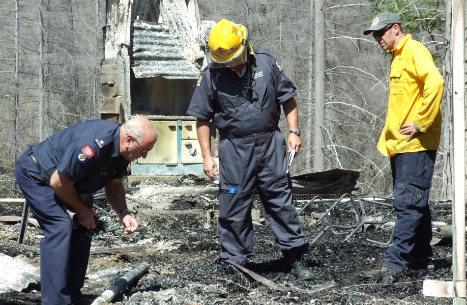 Fire and Emergency New Zealand officers and a police detective examine the scene of the Mount Aurum Homestead fire yesterday. 