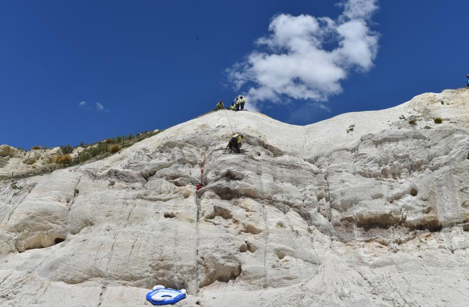 Cromwell firefighter Rowen Dunnet clings to Bowie after abseiling down a cliff (right) to rescue...