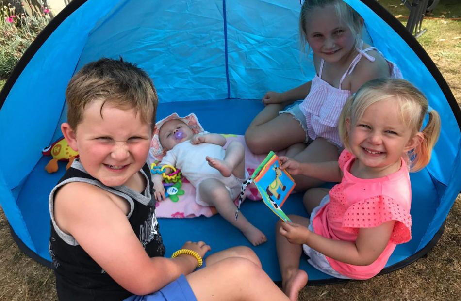 Cousins Liam Foley (5), Florence Harris (5 months), Annabelle Foley (7) and Payton McElrea (3) take cover from the sun at Lake Manapouri on New Year's Eve. Photo: Jamie McElrea