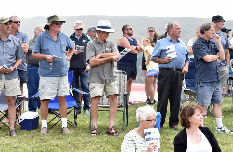 Punters all stand to watch the races.