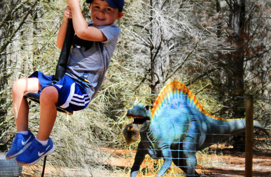Joshua Jamison (3) rides the flying fox watched by a Jurassic dinosaur sculpture at Highlands...