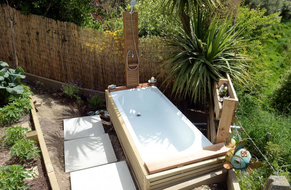 Screened by plants, the outdoor bath and shower serve two purposes: the owners can bathe under...