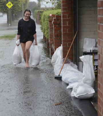 Shannon Goodwin helps sandbag her neighbour's property in Surrey St. Photo: Gerard O'Brien