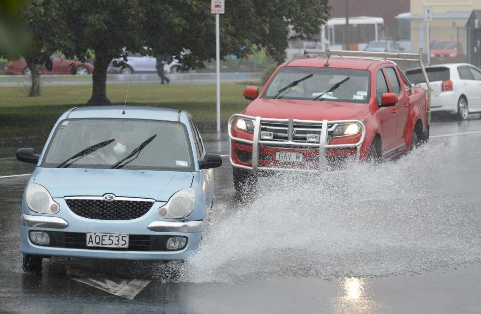 Motorists drive through a pool of water at the intersection of Andersons Bay Rd and Crawford St....