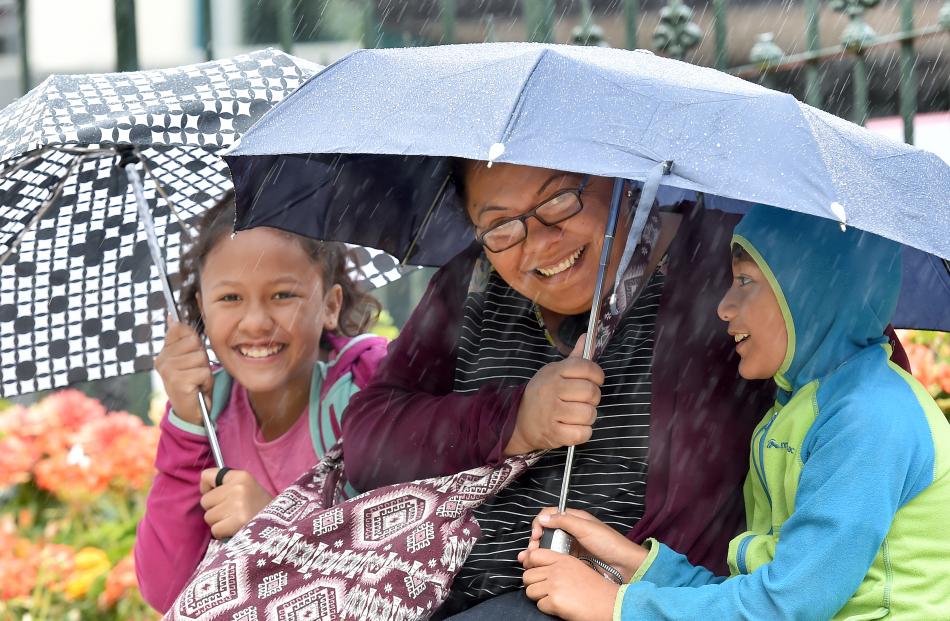 Taking cover during the celebrations in the Octagon are (from left) Jessica (10), Sarah and Joseph Tupai (8).