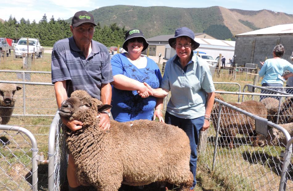 David Howden, of Gore, holds the two-tooth Romney ram sold by his daughter, Julie Howden (centre), as she and Christchurch buyer Janice Winter seal the $375 deal with a handshake. Photos: Sally Brooker
